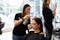 Hairdressing student sprays hairspray on client
